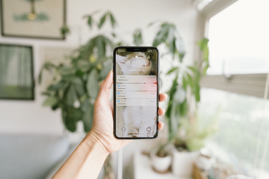 Hand holding smartphone in bright room receiving garage door monitor alert notification