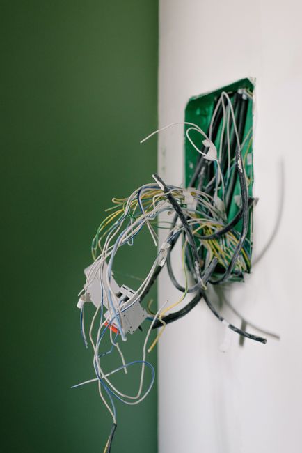 Wall outlet with wiring exposed during smart garage controller installation