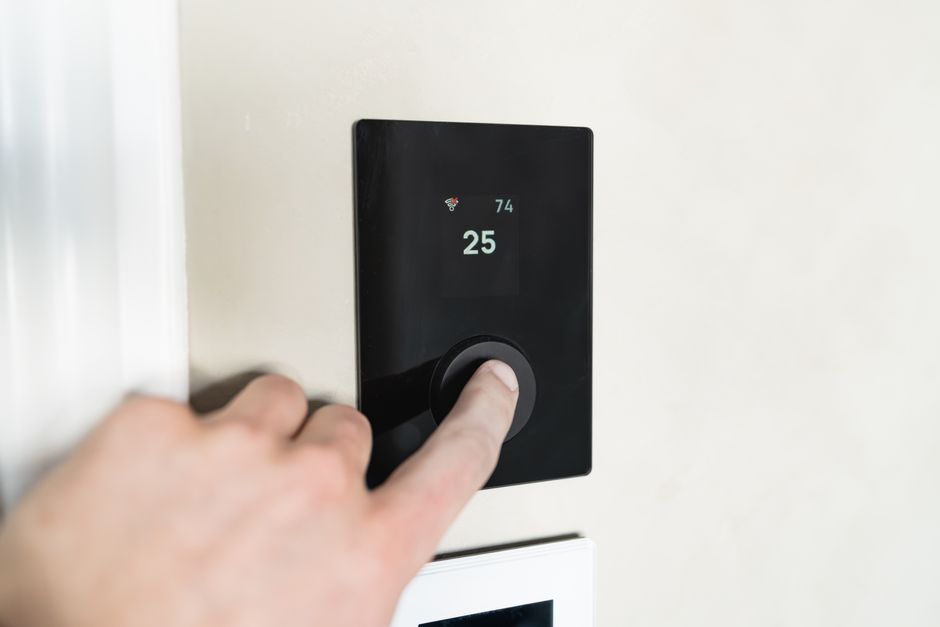 How to Factory Reset Your Ryobi Garage Door Opener 4 Hand adjusting smart device on wall representing Ryobi app re-pairing after reset