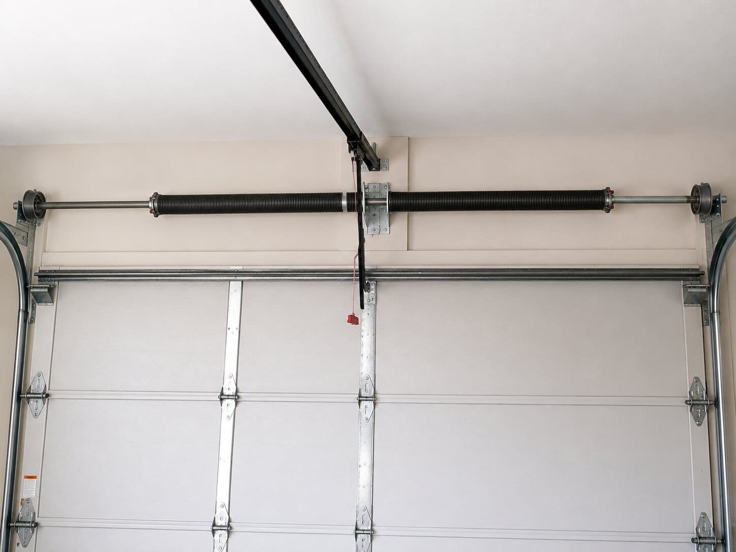 Garage door torsion spring assembly mounted above a closed garage door