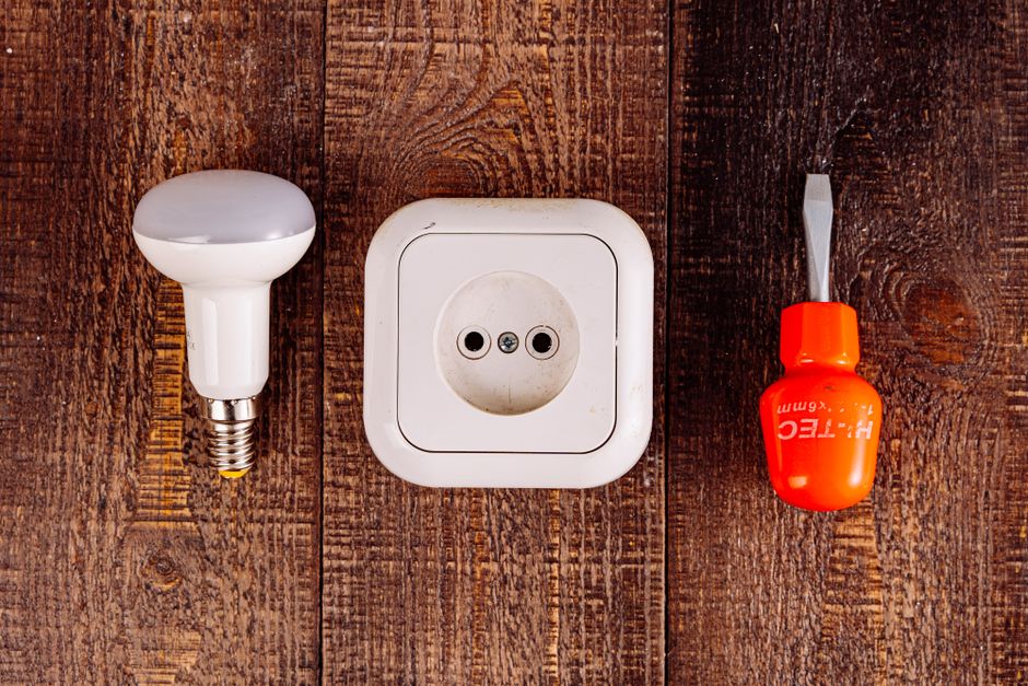 Extra Lights Controlled by the Garage Door Opener: 3 Ways That Work 2 Light bulb and socket with a screwdriver, representing the garage door opener light socket