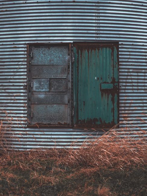 Close-up of a weathered metal door on a farm grain storage structure