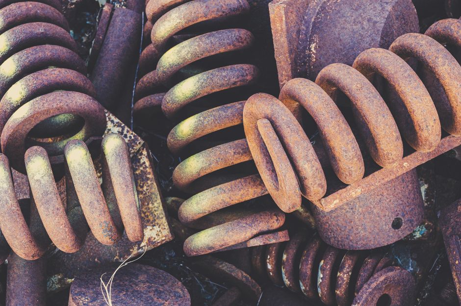 Best Garage Door Torsion Springs (2026 Picks by Cycle Life) 4 Weathered metal springs representing a standard-cycle torsion spring nearing replacement