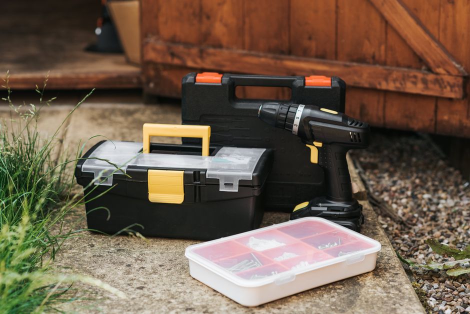 Best Garage Door Torsion Springs (2026 Picks by Cycle Life) 7 Electric screwdriver tool placed near a garage entrance for installation work