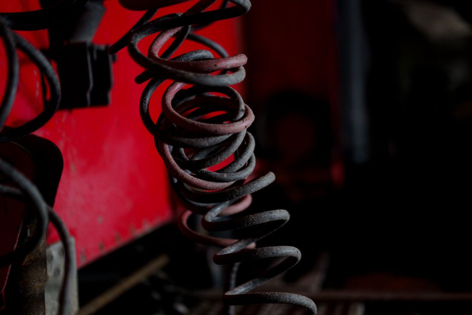 Best Garage Door Torsion Springs (2026 Picks by Cycle Life) 2 Close-up of coiled metal springs against an industrial backdrop
