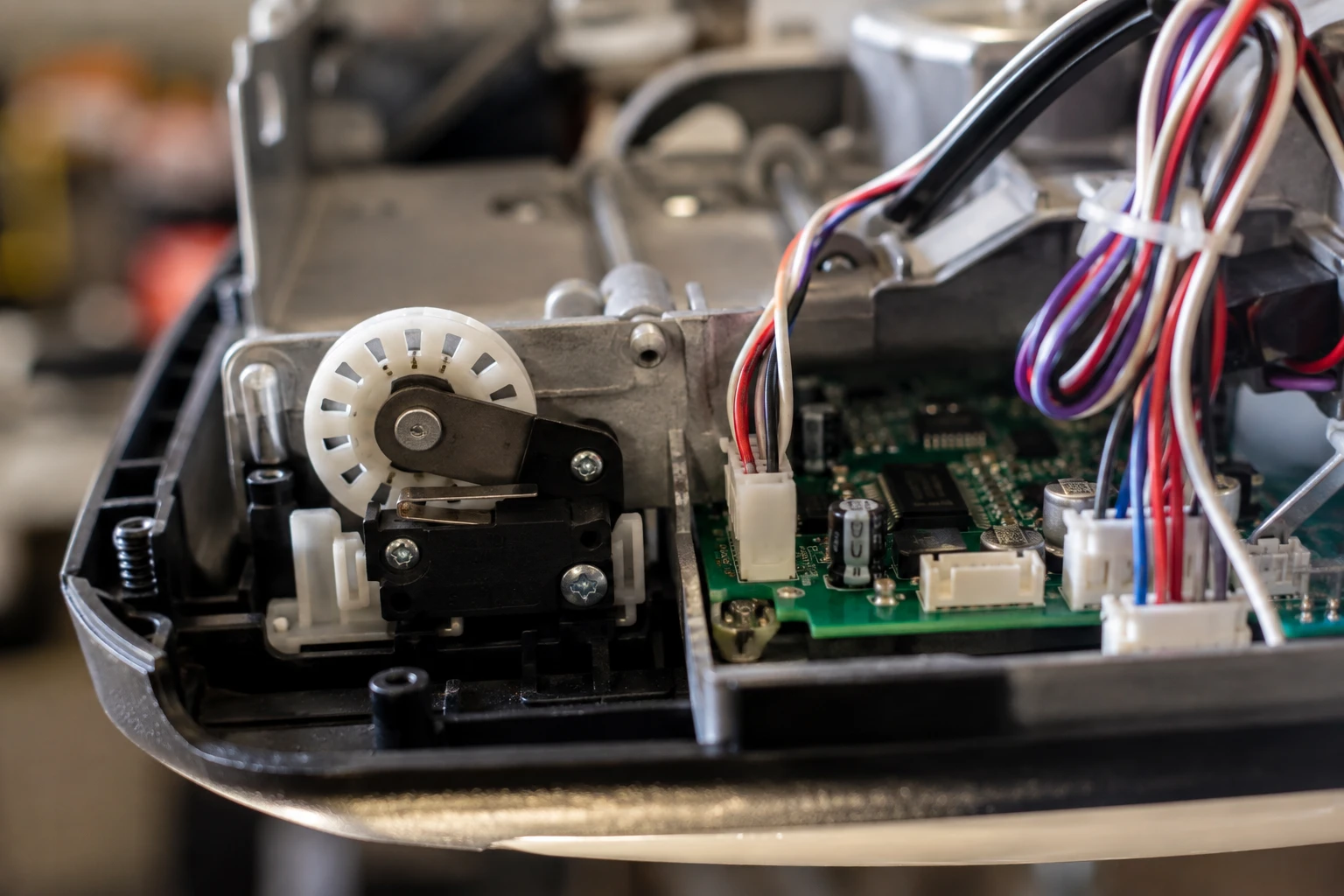 Close-up of the internal limit switch sensor wheel and circuit board that tells a Genie garage door opener when to stop