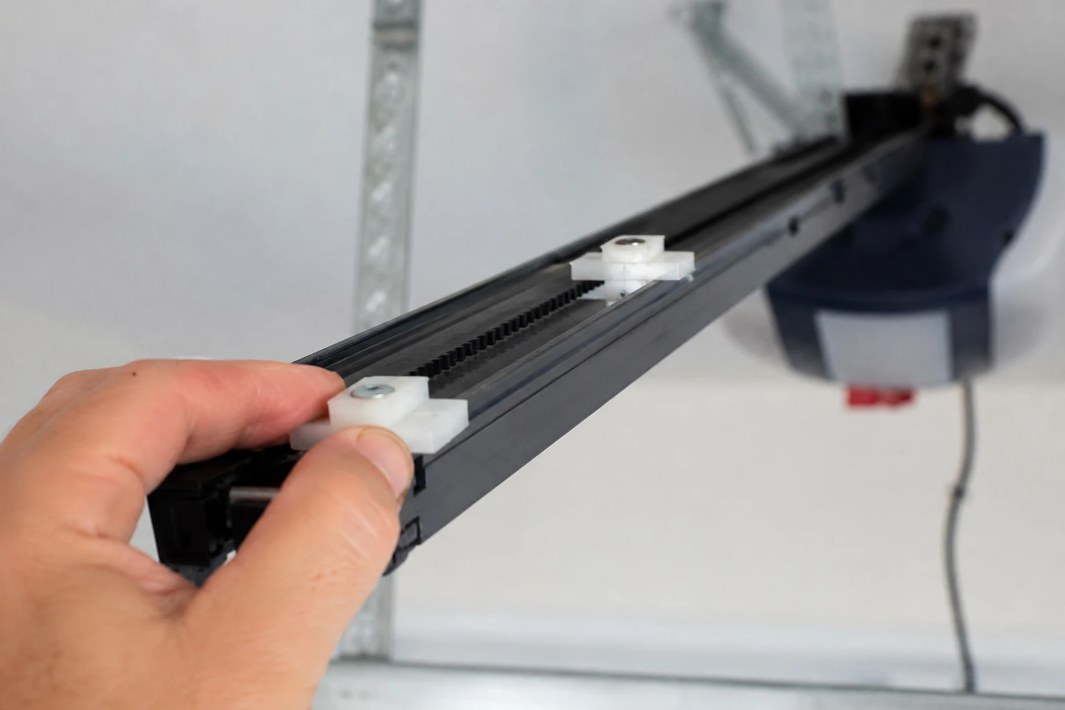 Hand sliding a white plastic limit tab along the drive rail of a Genie screw-drive garage door opener