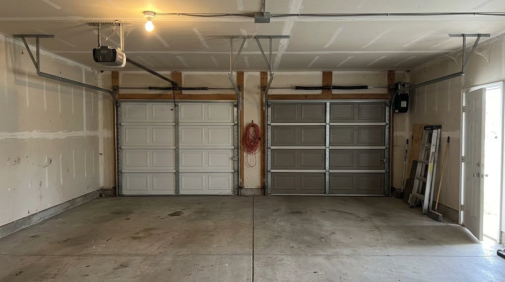 Two-car garage showing a traditional chain-drive opener on one door and a jackshaft wall-mount opener on the torsion bar of the other